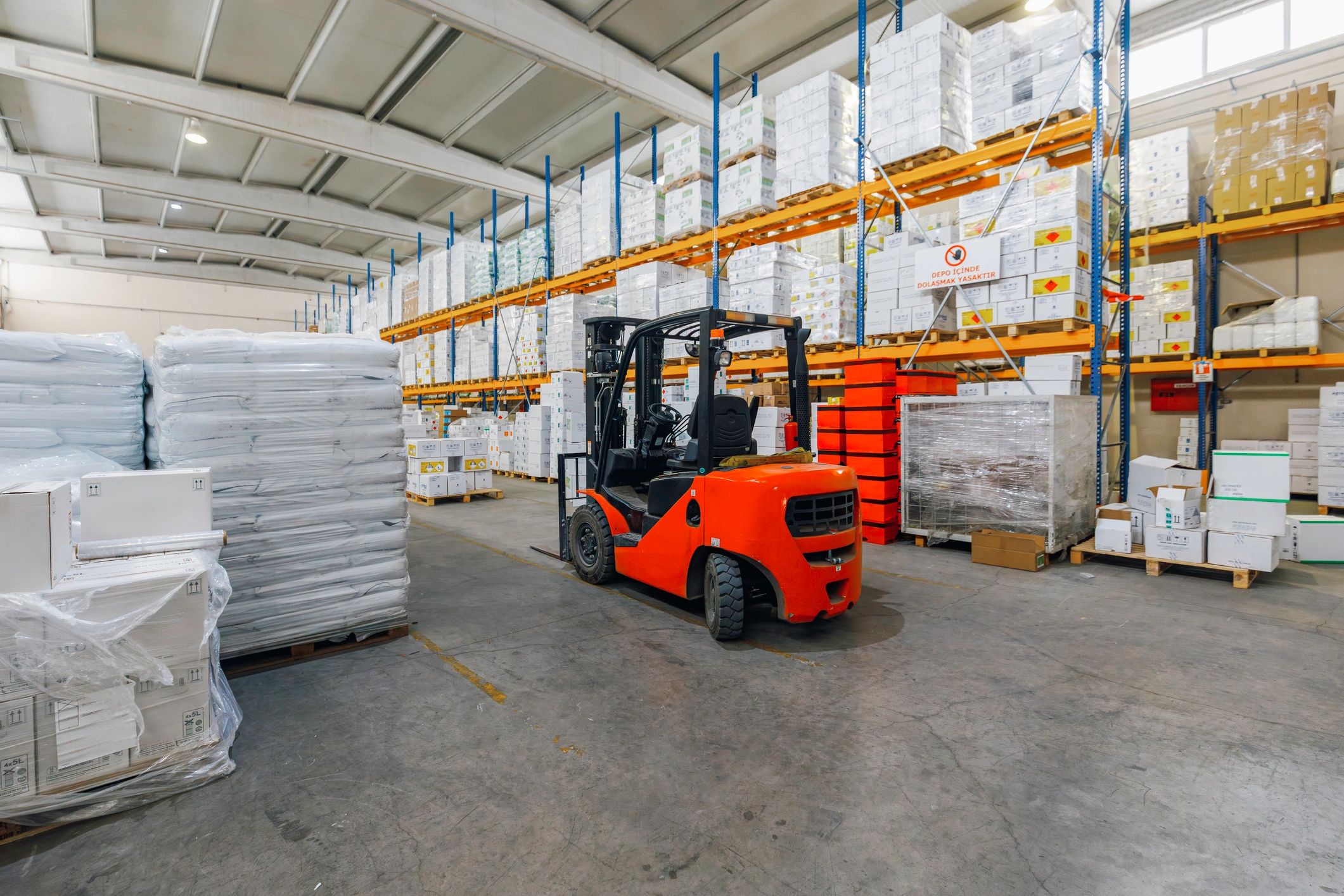 Forklift in a warehouse aisle with palletized goods ready for distribution